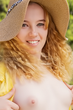 Yellow shirt dips on the wooden fence as Erika Fox poses with her straw hat